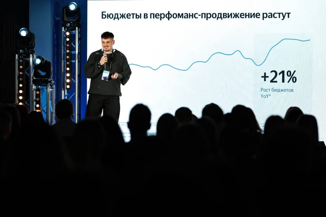 Тимур на сцене перед экраном с линейным графиком; на переднем плане силуэты слушателей.